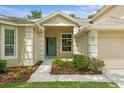Close-up of the home's entrance featuring a charming green door adorned with a wreath and manicured landscaping at 19207 Autumn Woods Ave, Tampa, FL 33647