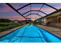 Spacious screened pool with sun loungers, and open views of the yard and pond in the distance at 2653 Longleaf Pine Pt, New Port Richey, FL 34655