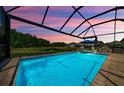 Screened pool with poolside seating overlooking a serene pond and natural preserve, offering a private oasis at 2653 Longleaf Pine Pt, New Port Richey, FL 34655