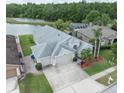 Aerial view of home featuring a three-car garage, screened in patio, lush greenery, and a serene lake at 29542 Forest Glen Dr, Wesley Chapel, FL 33543