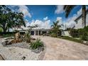 Attractive property enhanced by paver driveway, lush landscaping, mature palm trees, and solar panels at 333 Belleair Ne Dr, St Petersburg, FL 33704
