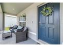 Inviting front porch with comfortable seating and a blue front door adorned with a floral wreath at 36398 Spanish Rose Dr, Dade City, FL 33525