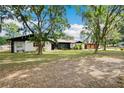 Lovely house displaying a vast front lawn, mature trees, and an attached garage with an extended driveway at 36601 Roberts Rd, Dade City, FL 33525