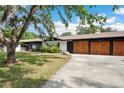 Side view of a home showing a multi-car garage with wooden doors and ample parking space at 36601 Roberts Rd, Dade City, FL 33525