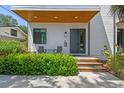 Inviting front porch featuring a wooden deck, black door, modern chairs, and lush greenery, perfect for relaxing at 411 W Frances Ave # 2, Tampa, FL 33602