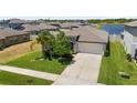 An aerial view of a single-Gathering home with a lush lawn, convenient two-car garage, and a serene lake view at 5208 Dandelion St, Apollo Beach, FL 33572
