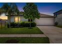 Well-maintained single-Gathering home with green lawn, landscaping, and a two-car garage at dusk at 5208 Dandelion St, Apollo Beach, FL 33572