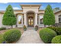 Stately entrance with stone walkway, manicured bushes, columns, and double doors, creating a welcoming and impressive facade at 10117 Breezy Pines Ct, Weeki Wachee, FL 34613