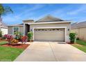 Inviting one-story home with a two-car garage and freshly landscaped front yard under a clear blue sky at 13414 Graham Yarden Dr, Riverview, FL 33579