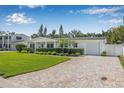 Charming single-story home with lush green lawn, manicured hedges, and a paved driveway leading to a garage at 1404 84Th N Ave, St Petersburg, FL 33702