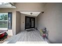 Inviting front porch with tiled floor leading to double front doors and gray exterior at 18408 Hanna Rd, Lutz, FL 33549