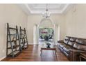 Open living room area featuring hardwood floors, coffered ceiling, pillars, chandelier and access to the screened-in patio at 20254 Ravens End Dr, Tampa, FL 33647