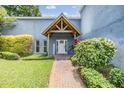 Charming home entrance with a brick walkway, beautiful landscaping, and a welcoming front door at 3938 Lake Joyce Dr, Land O Lakes, FL 34639