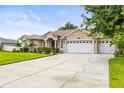 Charming single-story home boasting a three-car garage, lush landscaping, and a manicured lawn at 4615 Cozzo Dr, Land O Lakes, FL 34639