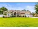 Single-story home with a well-maintained lawn, lush landscaping, and a convenient three-car garage at 4615 Cozzo Dr, Land O Lakes, FL 34639