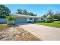 Inviting exterior with green garage door, well-maintained landscaping, and long driveway at 5647 110Th Way, Seminole, FL 33772