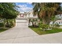 Two-story home with a covered porch, lush landscaping, an American flag, and an attached two-car garage at 6022 S Elkins Ave, Tampa, FL 33611