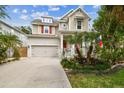 Inviting two-story home with lush landscaping, covered porch, American flag, and a two-car garage at 6022 S Elkins Ave, Tampa, FL 33611