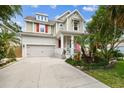 Inviting two-story home with mature landscaping, colorful flags, a covered porch, and a two car garage at 6022 S Elkins Ave, Tampa, FL 33611