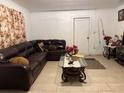 Cozy living room featuring tile flooring, a brown leather sofa, and a glass coffee table at 6206 Paul Buchman Hwy, Plant City, FL 33565