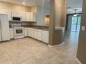 Well-lit kitchen boasts white appliances, tile flooring, and seamless flow into living area at 6304 Parkside Meadow Dr, Tampa, FL 33625