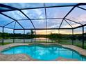 Screened-in pool with sunset view, and brick pool deck in backyard at 10911 Rockledge View Dr, Riverview, FL 33579