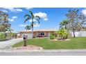 This charming home boasts a lush green lawn, palm trees, and colorful flowerbeds, creating a welcoming and picturesque front yard at 11535 64Th Ter, Seminole, FL 33772