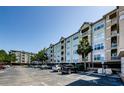 Multi-story building with neutral paint, balconies, and ample parking surrounded by mature trees and blue skies at 1216 S Missouri Ave # 108, Clearwater, FL 33756
