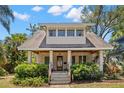 Charming home featuring a stone facade, covered porch, and lush landscaping with a beautiful gable roof at 146 8Th Ne Ave, St Petersburg, FL 33701