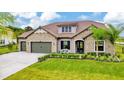 Charming single-story home features a stone facade, well-manicured lawn, and a two-car garage at 17804 Brewster Grn, Lutz, FL 33559