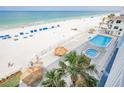 Sandy beach with lounge chairs, a pool, jacuzzi, and tiki huts, offering a relaxing resort experience at 18500 Gulf Blvd # 406, Indian Shores, FL 33785