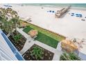 Sandy beach with clear water, a pier, and palm trees, plus manicured grounds and tiki umbrellas at 18500 Gulf Blvd # 406, Indian Shores, FL 33785