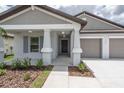 Close-up of front entrance with gray shutters, white columns, covered entrance and 2-car garage at 190 Rain Berry Ave, Ruskin, FL 33570