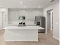 Modern kitchen features stainless steel appliances and an island with a sink at 20423 Symphony Pl, Venice, FL 34293