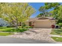 Charming single-story home featuring a well-manicured lawn, two-car garage and mature landscaping, creating an inviting curb appeal at 2550 Rolling View Dr, Dunedin, FL 34698
