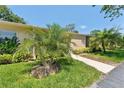 Attractive single-story home with manicured lawn, concrete walkway, and tropical palm trees at 2640 Woodgate Ln # F6, Sarasota, FL 34231