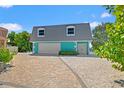 Charming turquoise waterfront home featuring a two-car garage, a paved driveway, and lovely curb appeal at 3021 Alton Dr, St Pete Beach, FL 33706