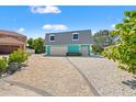 Charming turquoise waterfront home featuring a two-car garage, a paved driveway, and lovely curb appeal at 3021 Alton Dr, St Pete Beach, FL 33706