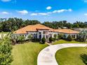 Stunning Mediterranean-style home with a circular driveway, lush landscaping, and a terracotta roof at 304 Hawk Talon Dr, Lithia, FL 33547