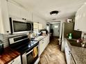 Well-lit kitchen featuring white cabinets, stainless steel appliances, and herringbone floors at 3970 56Th Ave N, St Petersburg, FL 33714