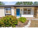 Welcoming front entrance with a bright blue door, stone accents, and manicured landscaping at 4018 Highgate Dr, Valrico, FL 33594