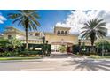 Community entrance with lush landscaping, palm trees and inviting architecture under a bright blue sky at 501 Knights Run Ave # 1335, Tampa, FL 33602