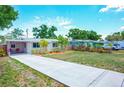 A charming home featuring a well-manicured lawn, covered carport, and coral colored front door that make for an inviting curb appeal at 5365 Flamingo Dr, St Petersburg, FL 33714