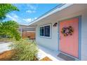 Charming home exterior featuring a coral-colored front door with a wreath, complemented by mature landscaping and fresh exterior paint at 5365 Flamingo Dr, St Petersburg, FL 33714