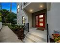 Contemporary home's entry showcasing a vibrant red door and manicured garden bed at 6904 S Macdill Ave # 1, Tampa, FL 33611