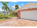 Spacious two-car garage attached to a brick home with a paver driveway and lush landscaping at 1141 80Th Street S Ct, St Petersburg, FL 33707