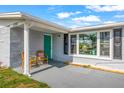 Close up of the home's entrance with a vibrant teal door and cozy seating area at 12700 5Th Isle, Hudson, FL 34667