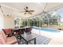 A screened-in patio with tables, chairs, fan, and view of pool offers space to relax and entertain at 1350 Mustang St, Nokomis, FL 34275