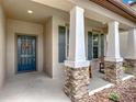 Welcoming front porch with stone pillars, rocking chairs, and a beautifully decorated blue front door at 15579 Stone House Dr, Brooksville, FL 34604