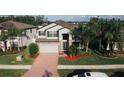 Aerial view of a charming home, showcasing its well-manicured lawn, brick-accented facade, and a spacious driveway at 19314 Long Lake Ranch Blvd, Lutz, FL 33558